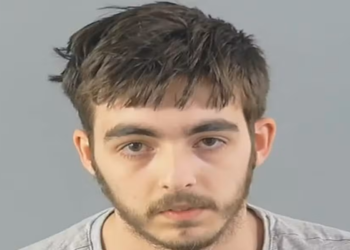 Carlo Tritta, 19 anos , em foto de custódia com cabelo castanho bagunçado, barba rala, expressão neutra e camiseta cinza.