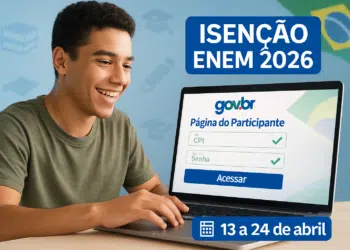 Estudante escreve em caderno com caneta enquanto notebook exibe logo do Enem ao lado de tela maior com marca do exame