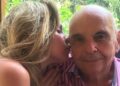 Ana Paula Renault beija a bochecha do pai, Gerardo Renault, que usa camisa listrada rosa e branca