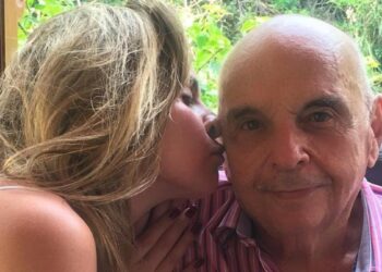 Ana Paula Renault beija a bochecha do pai, Gerardo Renault, que usa camisa listrada rosa e branca