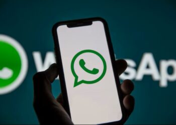 Celular com logo do WhatsApp na tela sendo segurado por uma pessoa